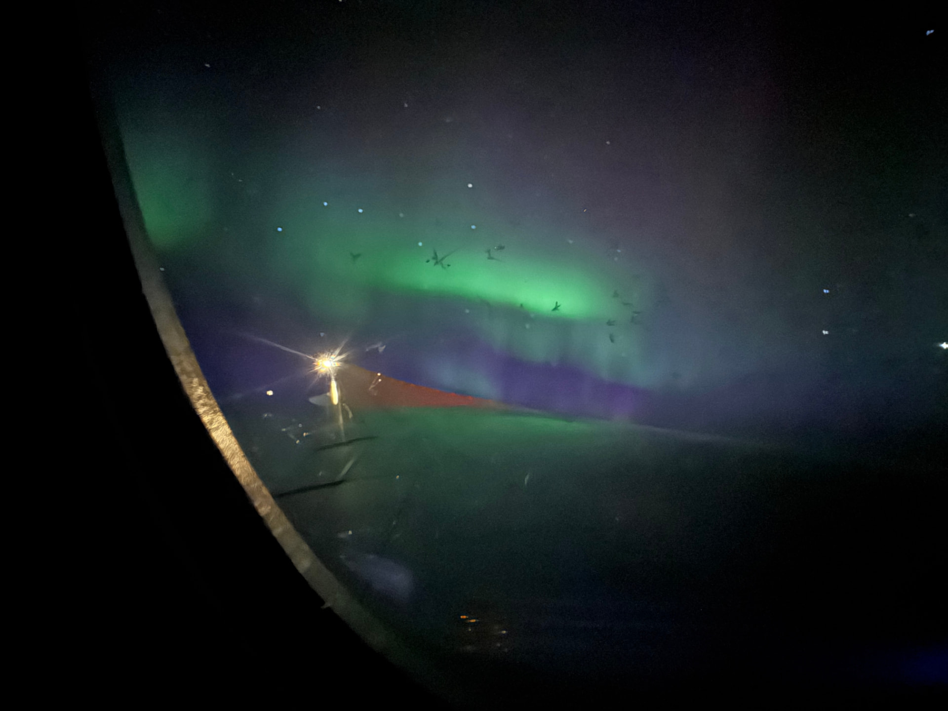 Green Northern Lights seen through an airplane window above the wing